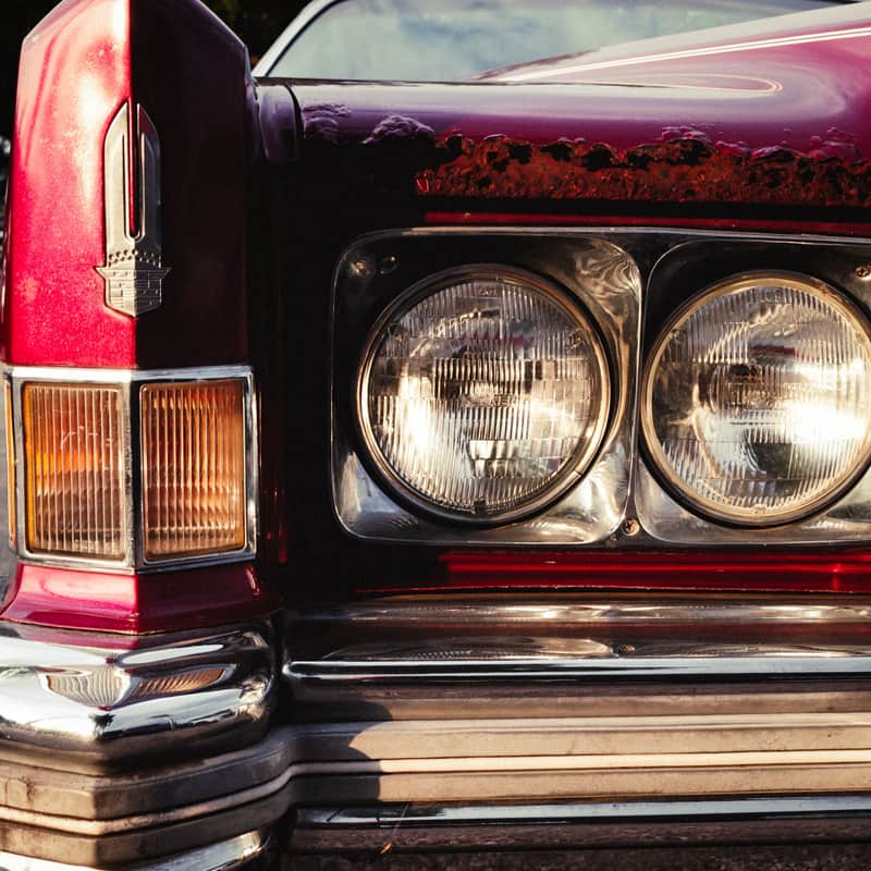 Twin headlamps of a red classic car